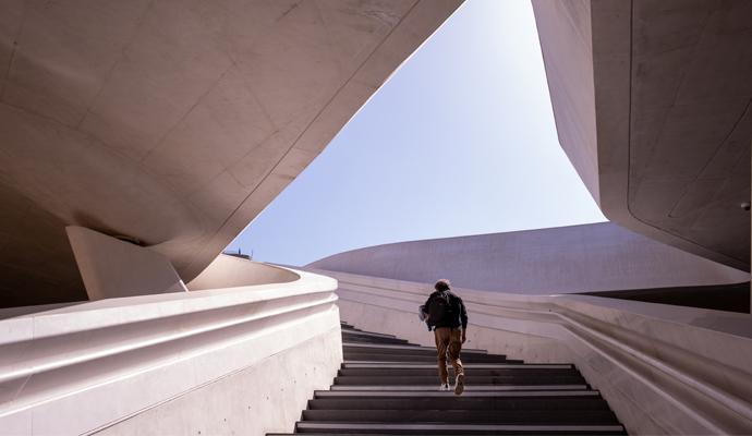 Unrecognised person walking at the stairs leading to a bright open space Unrecognised person walking at the stairs leading to a bright open space