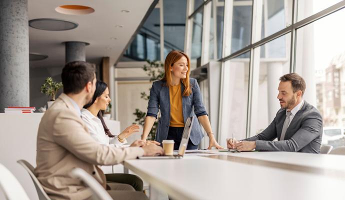 Female manager standing at corporate office with her leadership team and discussing business plan. Female manager standing at corporate office with her leadership team and discussing business plan.