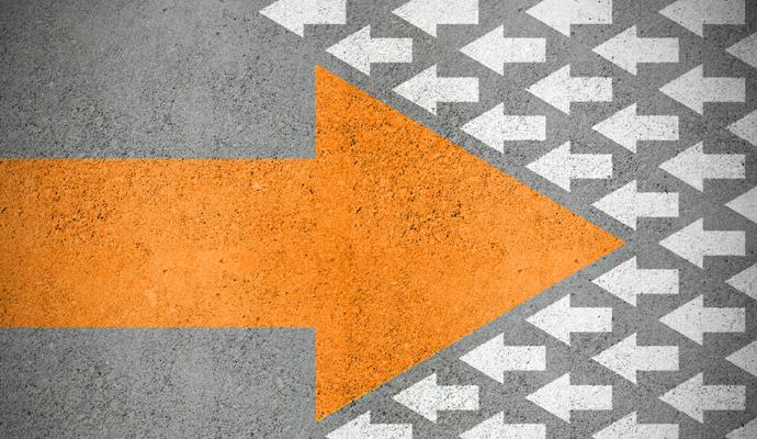 Strong orange arrow painted onto concrete, surrounded by smaller white arrows going in the opposite direction. Strong orange arrow painted onto concrete, surrounded by smaller white arrows going in the opposite direction.