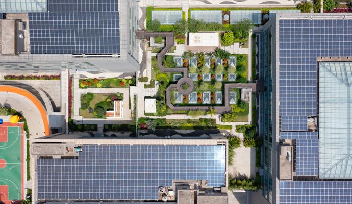 An overhead view of sustainably designed buildings shows rooftop gardens and solar panels