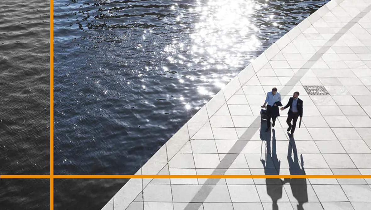 Two business professionals walk along a sunlit waterfront promenade Two business professionals walk along a sunlit waterfront promenade