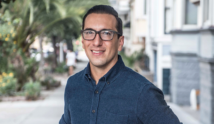 Stanford University psychology professor Jamil Zaki smiles while standing on a sidewalk.