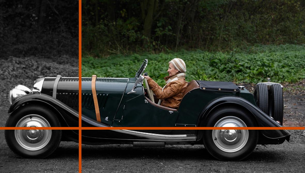 A woman drives an early-model classic car on a dirt road A woman drives an early-model classic car on a dirt road