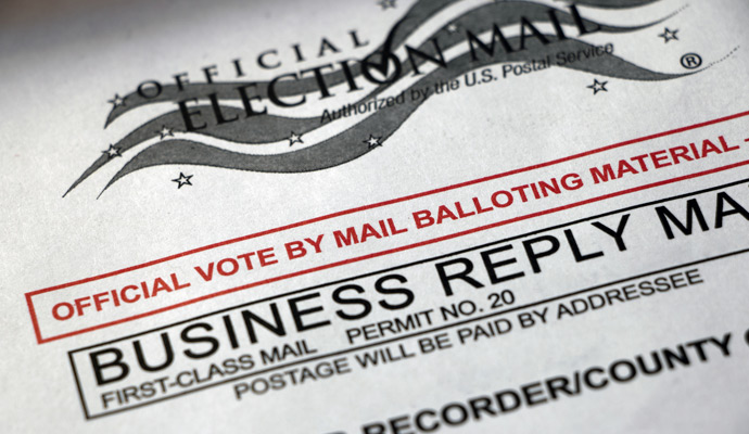 A close-up of a ballot envelope reads: Official vote-by-mail balloting material. A close-up of a ballot envelope reads: Official vote-by-mail balloting material.