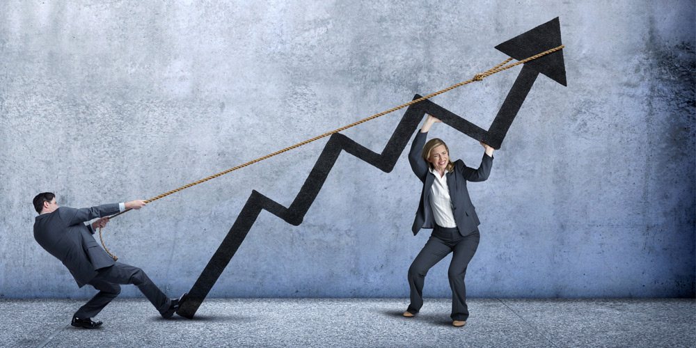 A businessman and a businesswoman work together to lift an oversized arrow, representing growth.