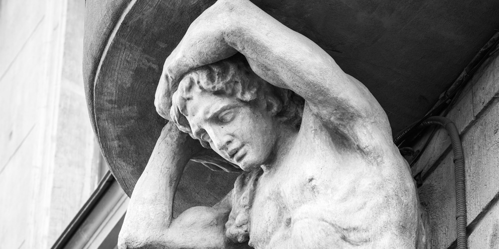 A photo of a sculpture of Atlas on the facade of an old house.