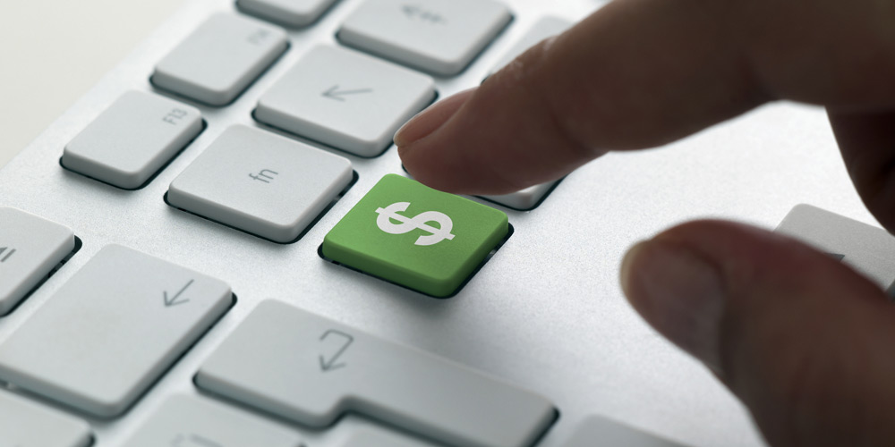 A finger hovers over a green dollar sign on a computer keyboard, indicating a digital purchase about to occur. A finger hovers over a green dollar sign on a computer keyboard, indicating a digital purchase about to occur.