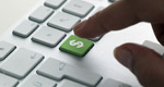 A finger hovers over a green dollar sign on a computer keyboard, indicating a digital purchase about to occur.