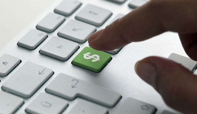 A finger hovers over a green dollar sign on a computer keyboard, indicating a digital purchase about to occur. A finger hovers over a green dollar sign on a computer keyboard, indicating a digital purchase about to occur.