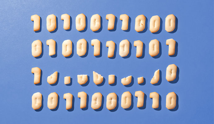 A grid of cookies — including some that are crumbled and broken — baked in the shape of binary code ones and zeros, against a blue background.