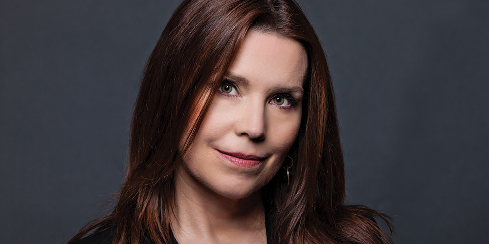 Photo of Annie Duke, a poker player turned strategy consultant, in a black shirt, smiling, with her head tilted to the side.