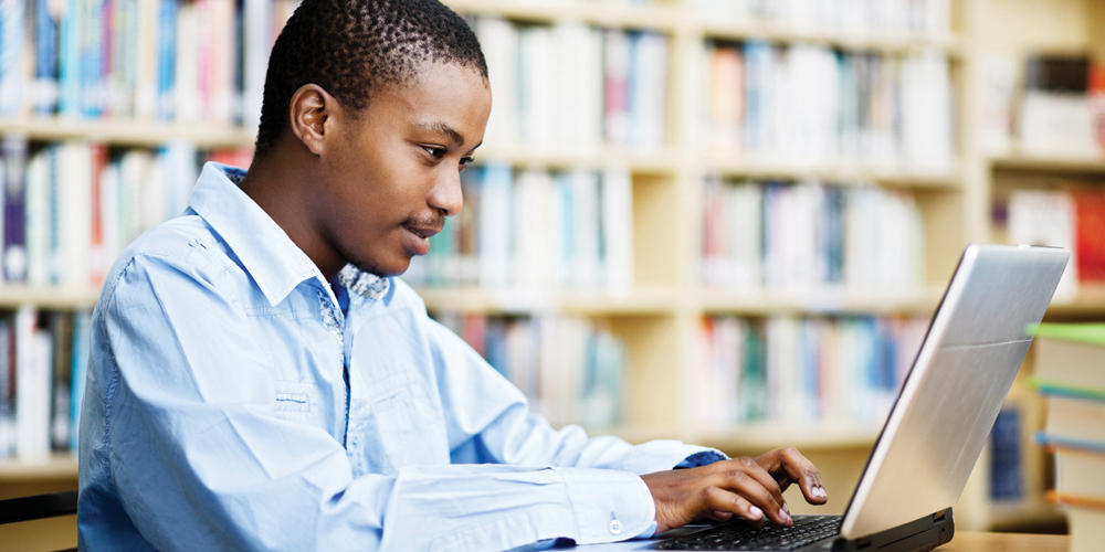 Young man works on a laptop in a library