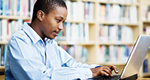 Young man works on a laptop in a library
