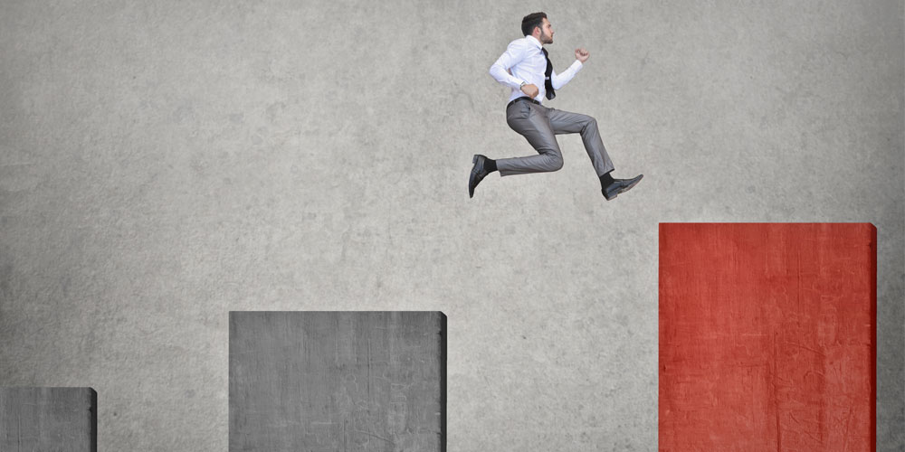 A businessman leaps from a gray bar on a chart to a higher red bar. A businessman leaps from a gray bar on a chart to a higher red bar.