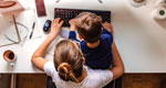 Overhead view of mother working on computer with her young son sitting in her lap.