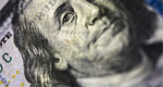 A close-up view of a US$100 bill frames a concerned-looking Benjamin Franklin.