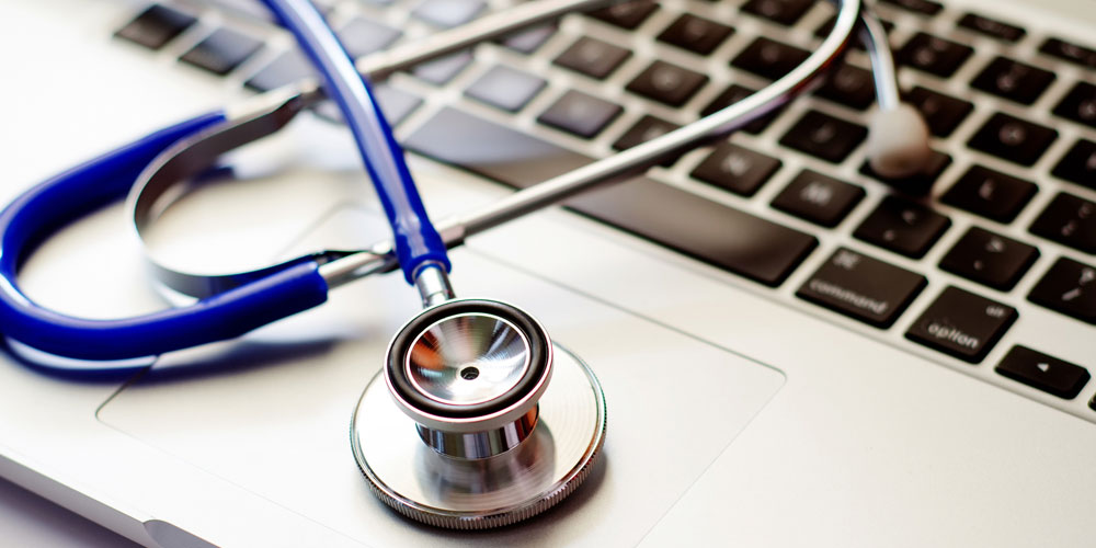 A stethoscope rests upon a laptop keyboard.