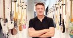 Fender CEO Andy Mooney pauses in a hallway lined with guitars.