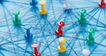 An arrangement of colorful pins linked together with string on a pale blue background suggests a network of connections.