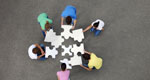 Six people seen from above, putting together giant jigsaw puzzle pieces