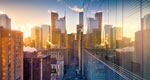 A photograph of the Toronto cityscape at sunrise, with the windows of one of the buildings reflecting the others.