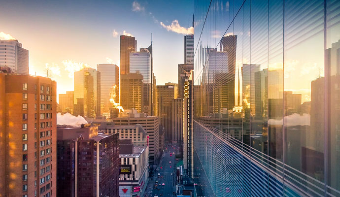 A photograph of the Toronto cityscape at sunrise, with the windows of one of the buildings reflecting the others. A photograph of the Toronto cityscape at sunrise, with the windows of one of the buildings reflecting the others.