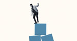 Man balancing atop an unstable stack of blue boxes