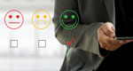 Torso and hands of a man using a smartphone. To his left is an overlay of the image on his screen: a rating system for customer service with a frowning face, a neutral face, and a smiling face. The smiling face is selected.