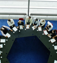 A board of directors meets at a large, round table.