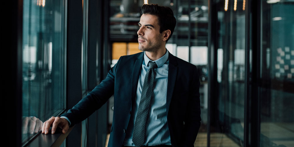 An introspective businessperson gazes through a window. An introspective businessperson gazes through a window.