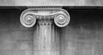 A black-and-white photo showing an architectural detail of an ionic column capital.