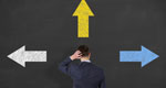 Confused businessperson, seen from behind, looking at many arrows on a blackboard, as if trying to discern the best way forward