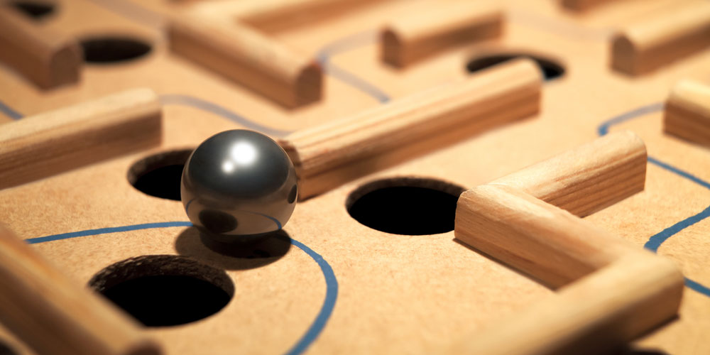A metal ball navigates a labyrinth maze of holes