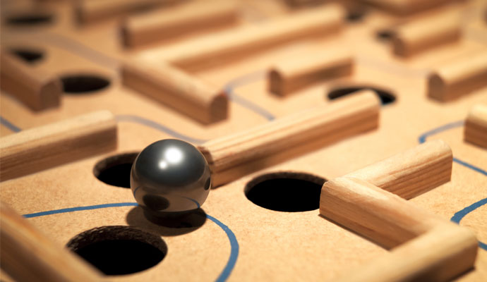 A metal ball navigates a labyrinth maze of holes