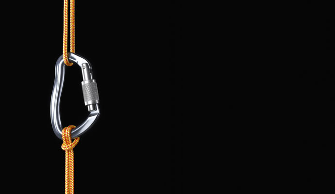 Two orange climbing ropes are connected by a carabiner. Two orange climbing ropes are connected by a carabiner.