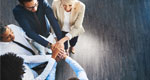 A group of co-workers in an office join hands together in unity