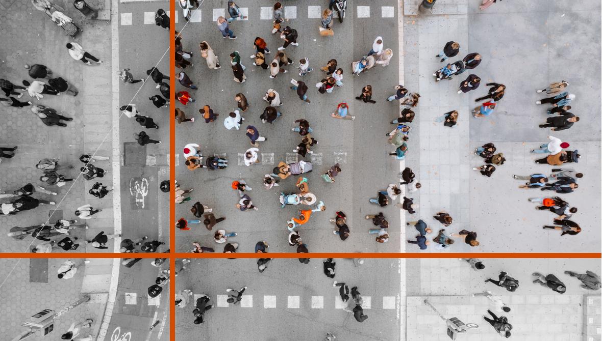 An overhead city view shows a crowd of people crossing an intersection from all directions.