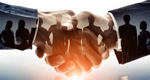 A silhouette of a group of businesspeople layered over a closeup photo of a handshake
