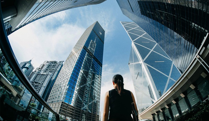 A photograph of a woman gazing at skyscrapers towering above her. A photograph of a woman gazing at skyscrapers towering above her.