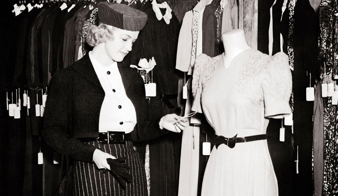 1930s woman checking price of a dress in a department store