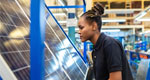 A photograph of a woman in a factory working on a solar panel.
