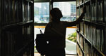 A student examines books in an academic library.
