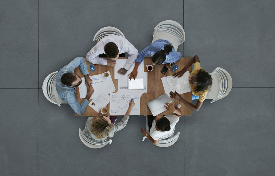An overhead view of a group of businesspeople gathered around a table for a lively, engaging meeting.