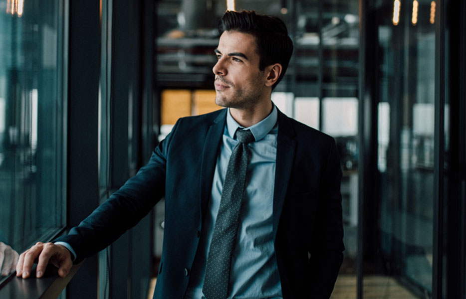 An introspective businessperson gazes through a window.