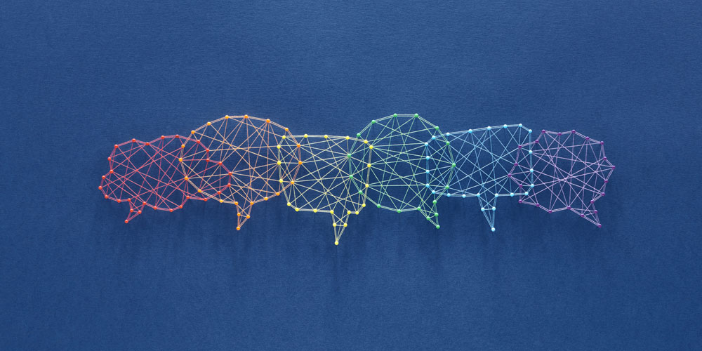 A network of pins and threads forms the shape of interconnecting speech bubbles, representing inclusion. A network of pins and threads forms the shape of interconnecting speech bubbles, representing inclusion.