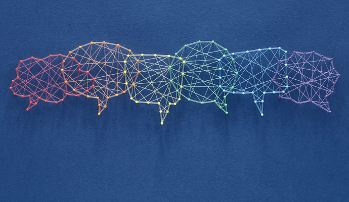 A network of pins and threads forms the shape of interconnecting speech bubbles, representing inclusion.