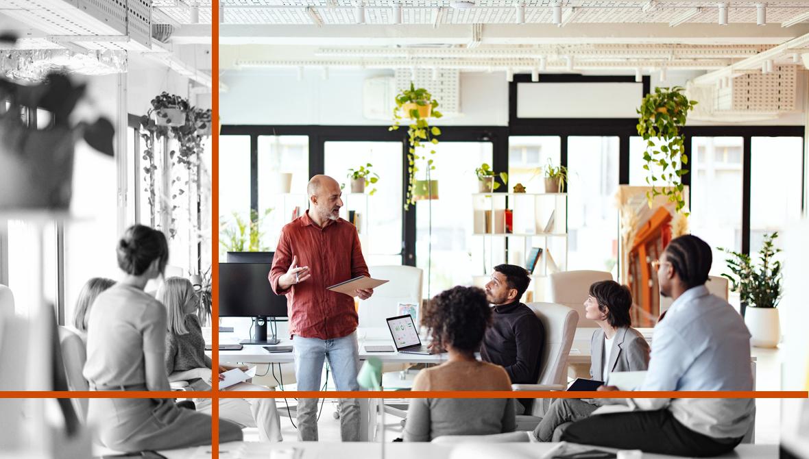 A small team of coworkers in casual dress meets in a bright, open workspace.