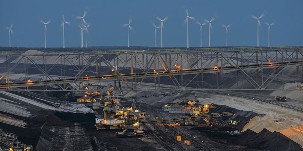 A photo of bucket-chain excavators in a lignite mine with wind turbines in the background in Cottbus, Germany
