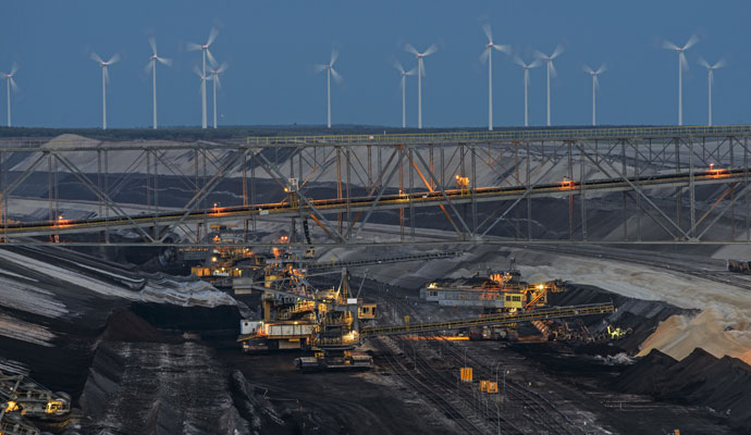 A photo of bucket-chain excavators in a lignite mine with wind turbines in the background in Cottbus, Germany