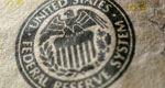A close-up view of a US$100 bill shows the seal of the US Federal Reserve.